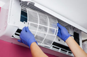 A person performing maintenance on an air conditioning unit by cleaning the filter to ensure optimal performance and air quality.